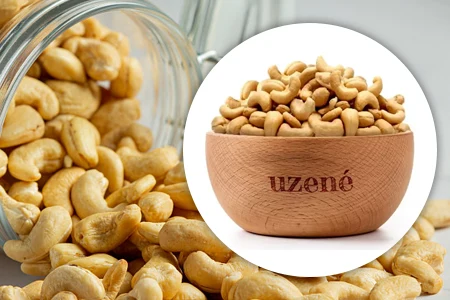 Kešu ořechy v dřevěné misce a sklenici na pozadí.