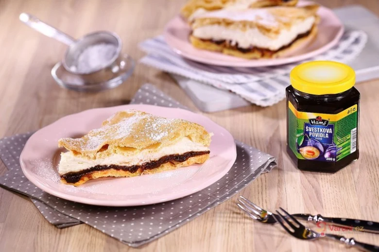 Kousek koláče s povidlovou náplní na růžovém talíři.