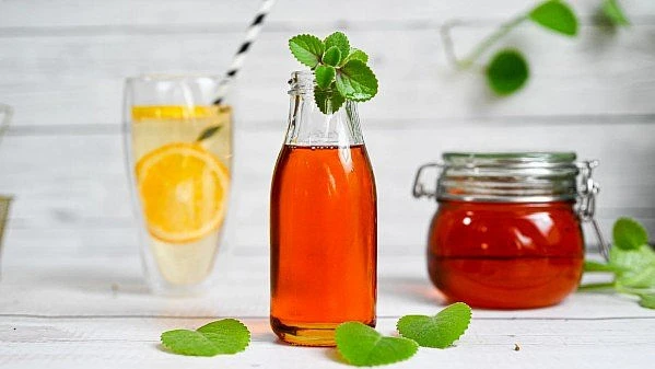 Sklenička s ovocným sirupem, džem a sklo se citronovou vodou.