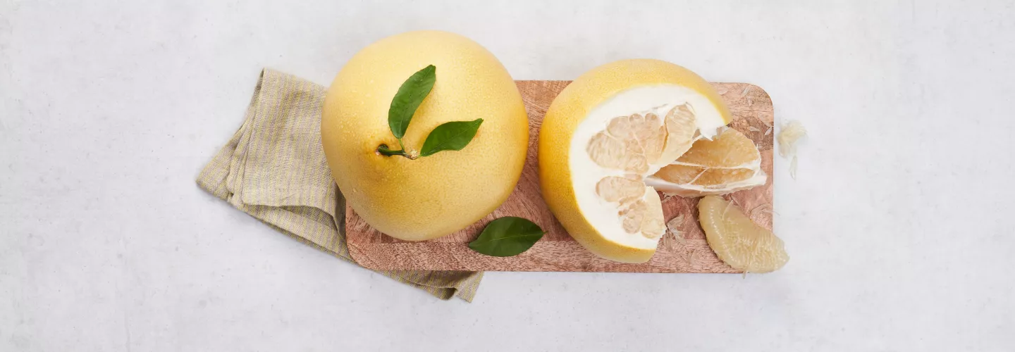 Celý žlutý pomerančový citrus s listy položený na dřevěné desce.