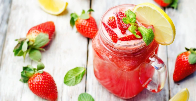Sklenice s jahodovou limonádou ozdobená mátou a citronem.