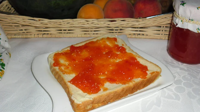 Kousek chleba s marmeládou z melounu na bílém talíři.