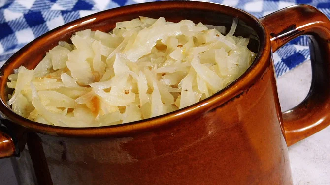 Připravené sladko-kyselé zelí v hrnku na modro-bílém ubrusu.
