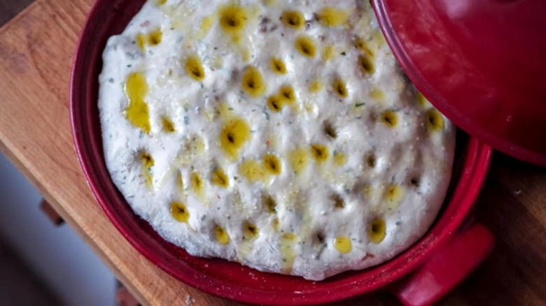 Nepečená italská focaccia s olivovým olejem v červeném hrnci.