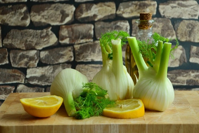 Čerstvý fenikel s citronem a koprem na dřevěném prknu.