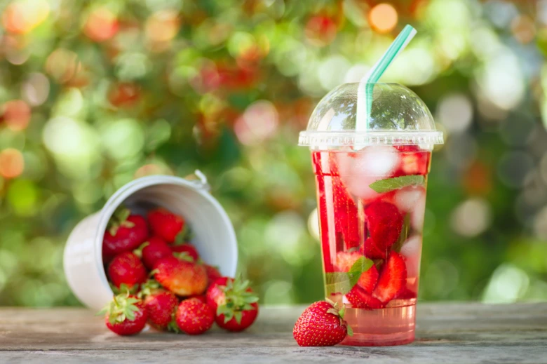 Domácí limonáda ze jahod s mátou v plastovém poháru.