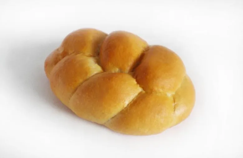 Zlatohnědá houska upletená do tvaru svazku.