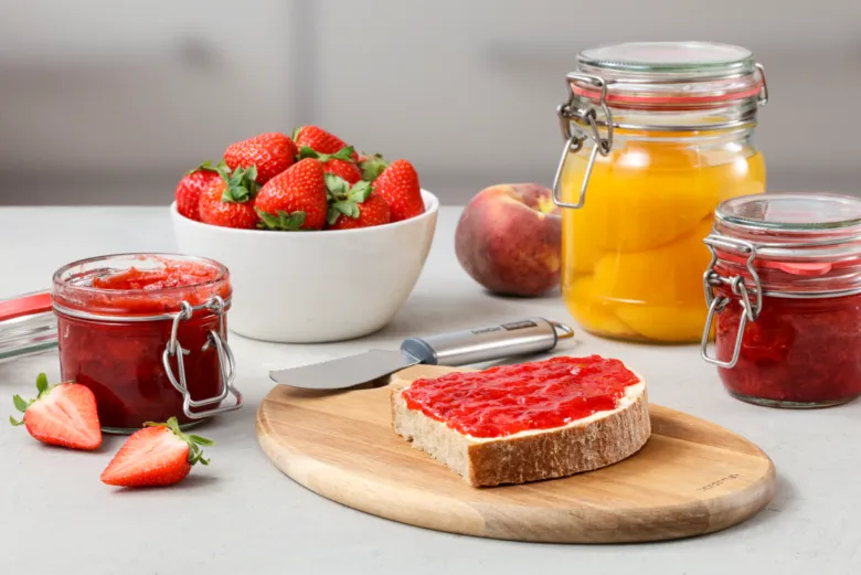 Domácí jahodová marmeláda na chlebu s čerstvými jahodami.