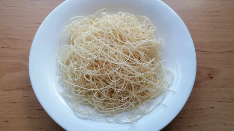 Sušené nudle kadiíf na bílém talíři před pečením.