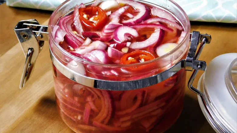 Sklenice nakládané červené cibule s chilli v nálevu.