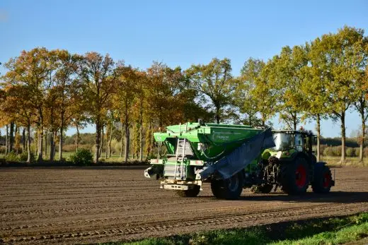 Traktor rozšiřuje hnojivo na poli v podzimním prostředí.