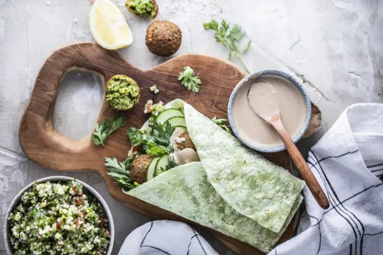 Připravený falafel s oblohou na dřevěném podnosu.