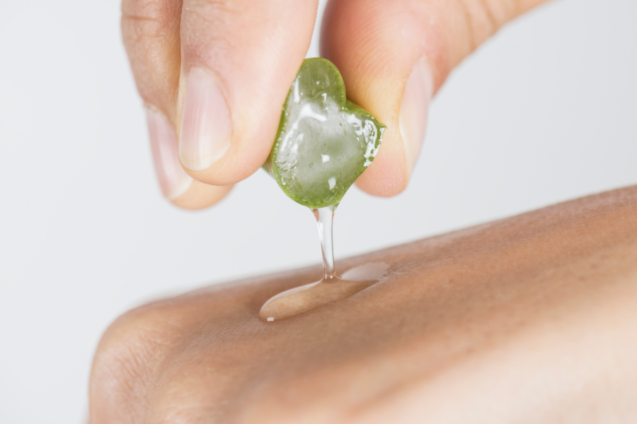 Ruka stlačí čerstvý list aloe vera na kůži.