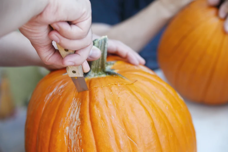 Ruce řezou dýni nožem pro vyřezávání vzorů na Halloween