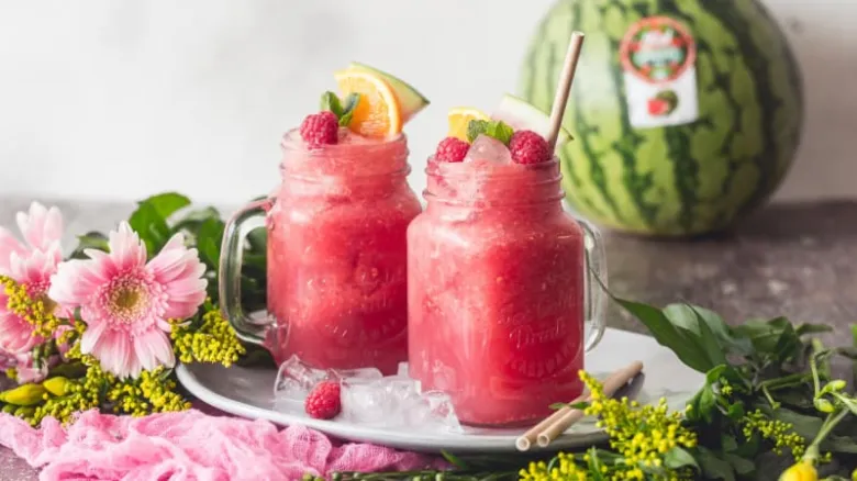 Dva sklenice okurkové limonády s ovocem na talíři.