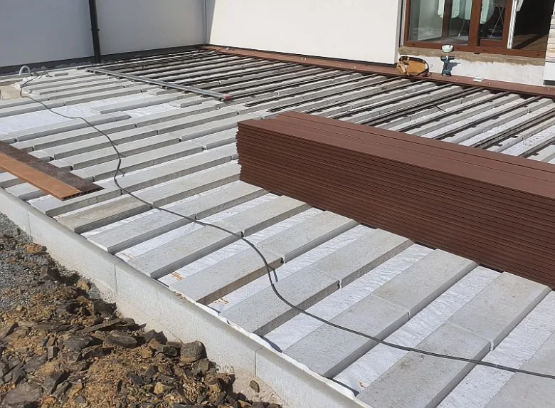 Montáž terasových prken z kompozitového materiálu na dřevěných trámech.