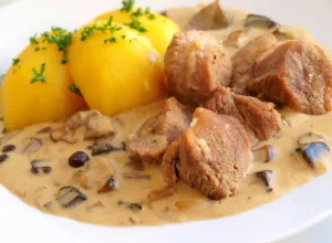 Maso s houbami v omáčce a vařenými bramborami na talíři.