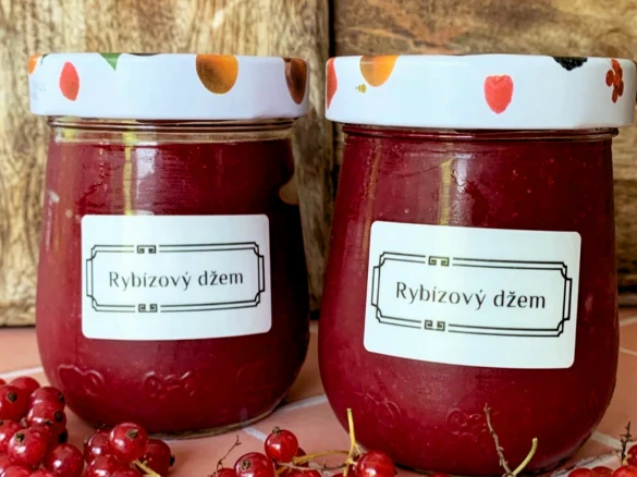 Dva sklenice s černorýbím džemem obklopené čerstvými bobulemi.