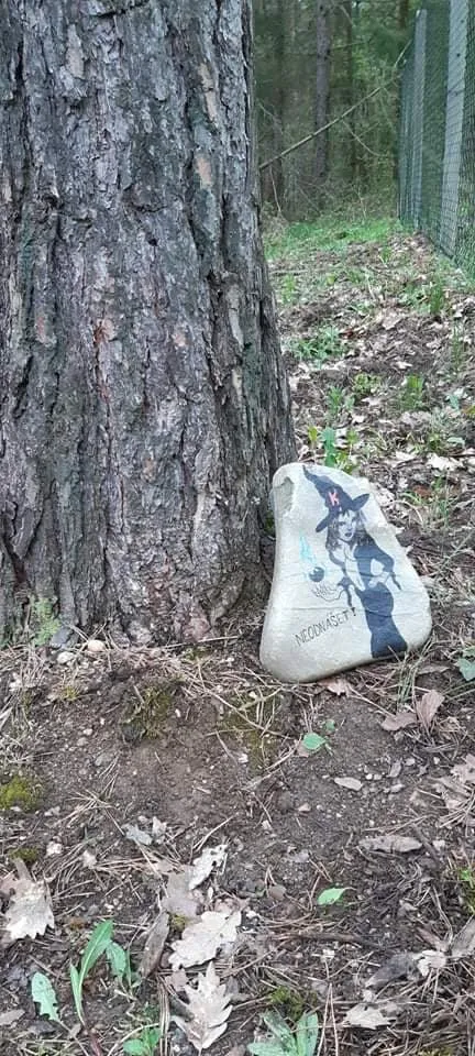 Kamínek namalovaný s postavou čarodějnice u stromu v lese.
