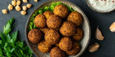 Zlatohnědé falafele v misce s čerstvou petrželkou a ingrediencemi.