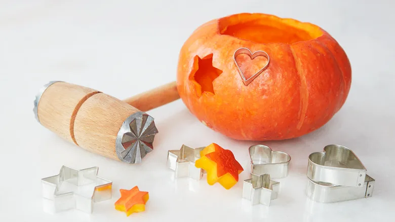 Nakrájená dýně s nástroji na vyřezávání vzorů pro Halloween.