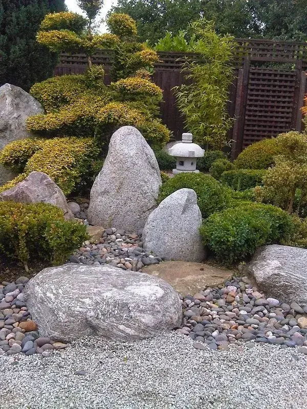 Japonská skalní zahrada s kameny, keři a bambusem.