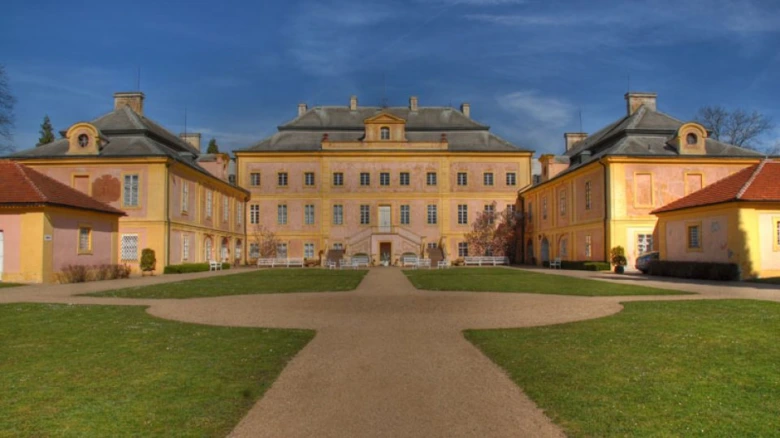 Historický dvůr s úhlednou zahradou kolem hlavní budovy.