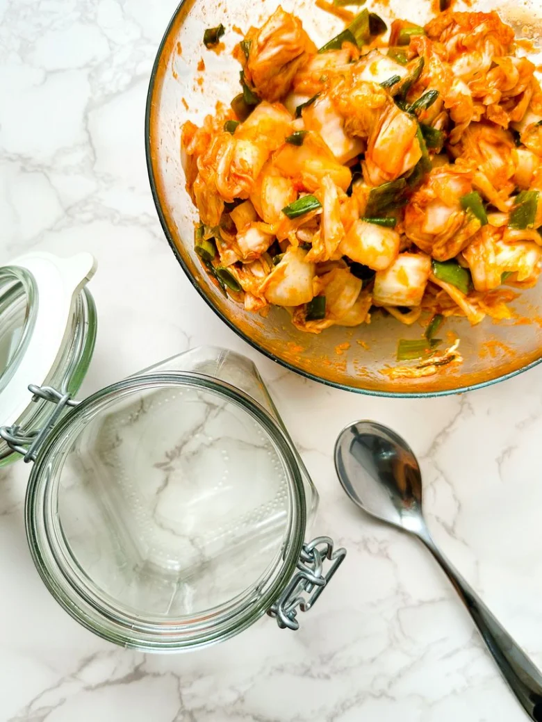 Domácí kimchi v míse s prázdnými skleněnými nádobami na fermentaci.
