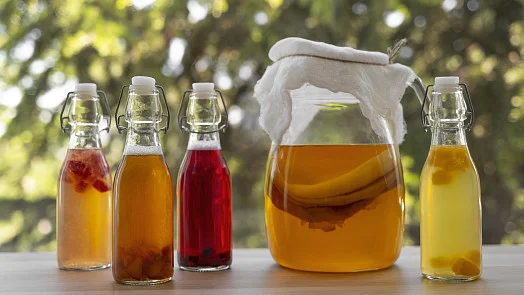 Sklenice s fermentovaným čajem kombucha na stole venku.