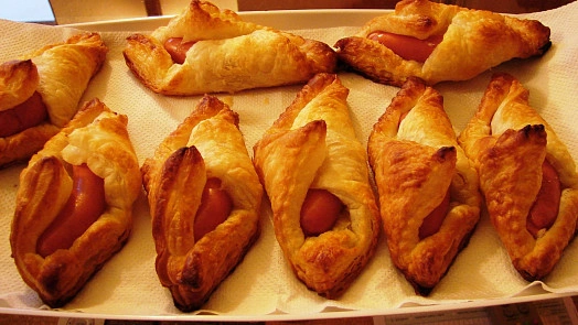 Zlatohnědé pečené párky v listovém těstíčku na podložce.