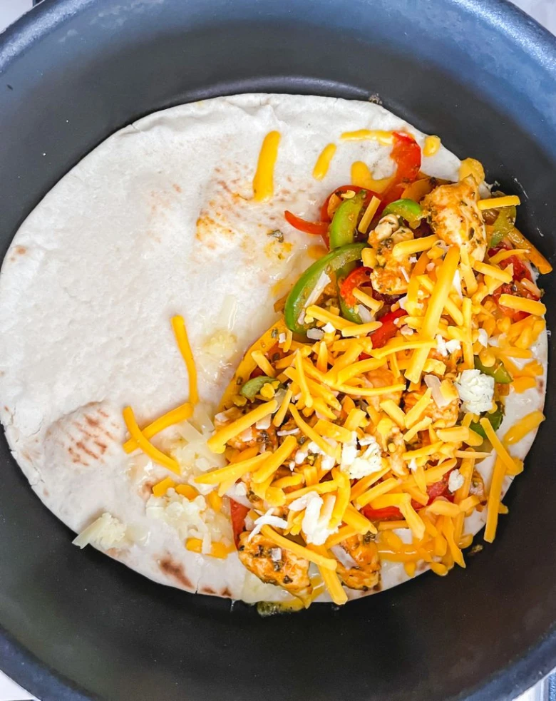 Tortilla s kuřetem, paprikou a sýrem v pánvi.
