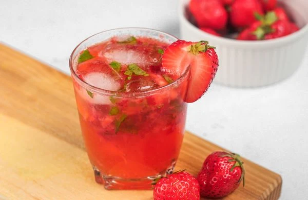 Nealkoholické Mojito s jahodami v sklenici na dřevěném podkladu.